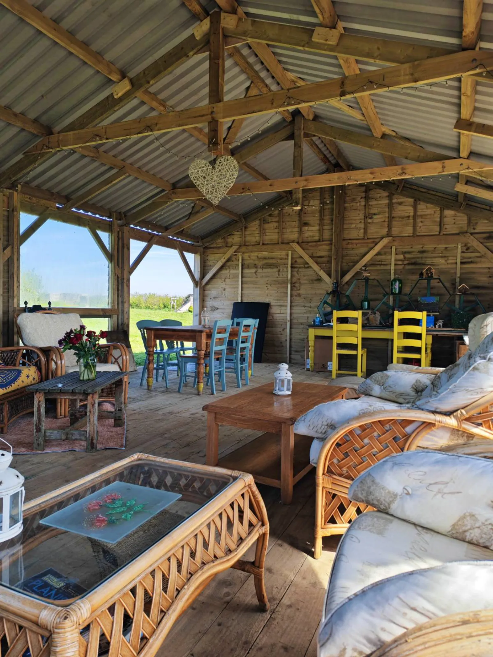 The Coffee Room lounge area with rattan armchairs, dining table, and arts and crafts corner at West Kellow Yurts
